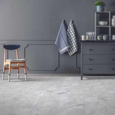 Stylish kitchen or dining area with dark gray paneled walls, light marble-patterned tile flooring, a wooden chair with a blue cushion, and a dark gray cabinet with open shelving.